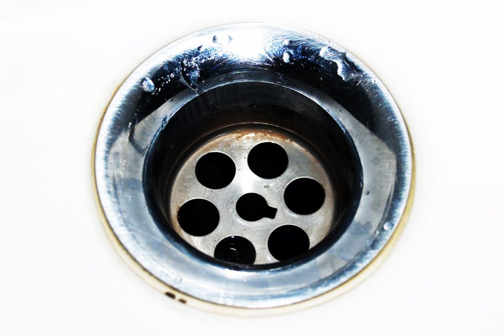 Close-up of a chrome sink drain with water droplets