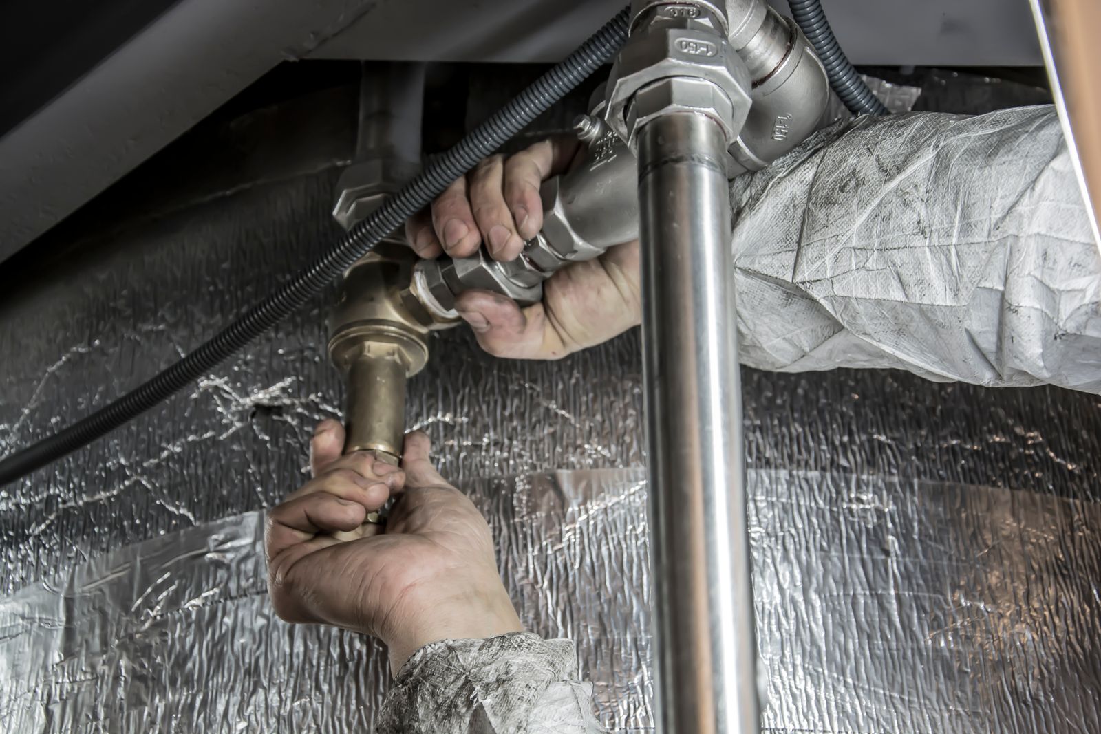 Plumber's hands fitting a steel water pipe joint indoors