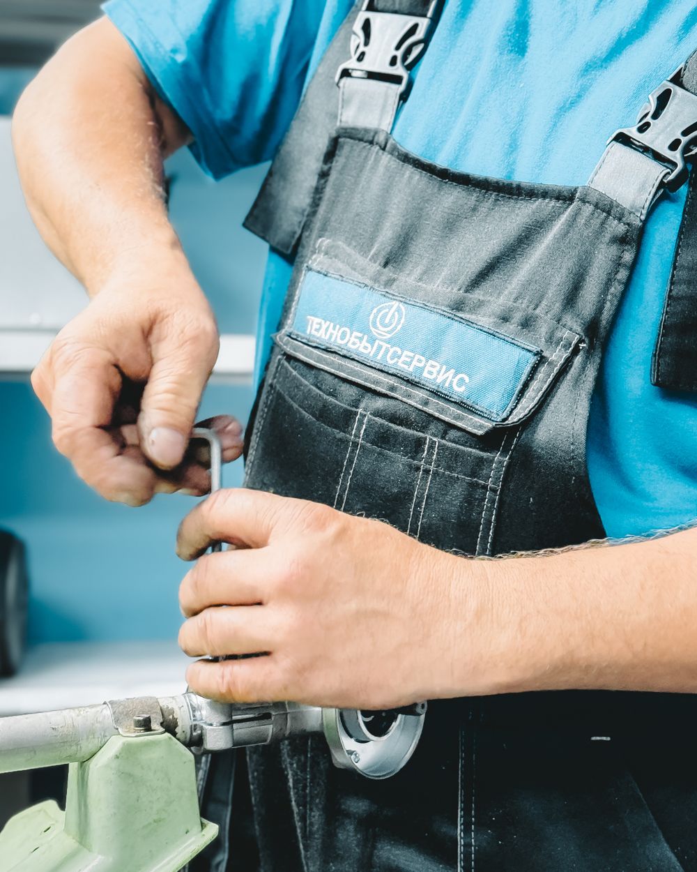 Plumber in a blue uniform tightening a pipe fitting with a wrench