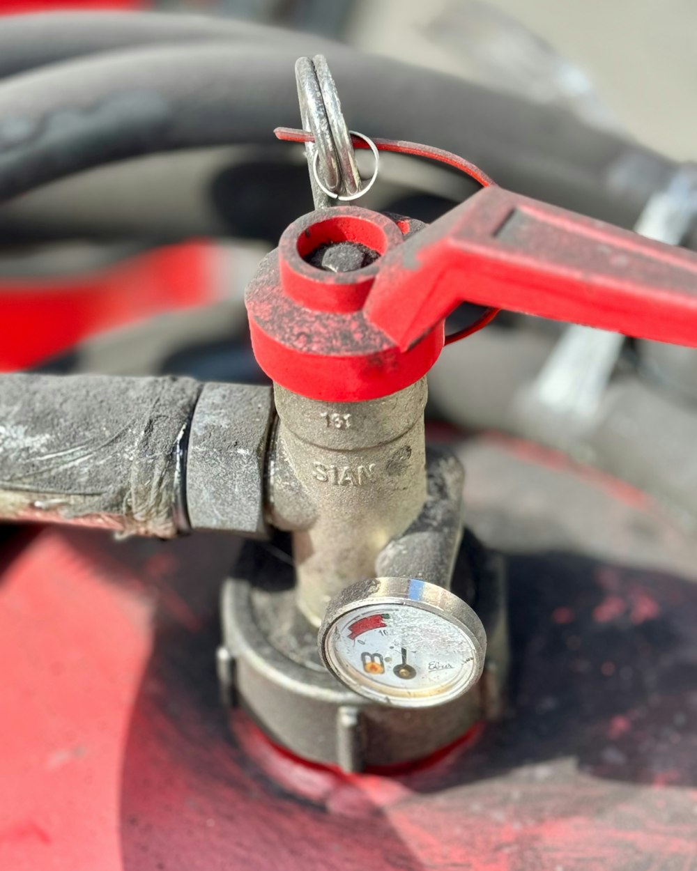 Pressure gauge and red valve on a water supply line